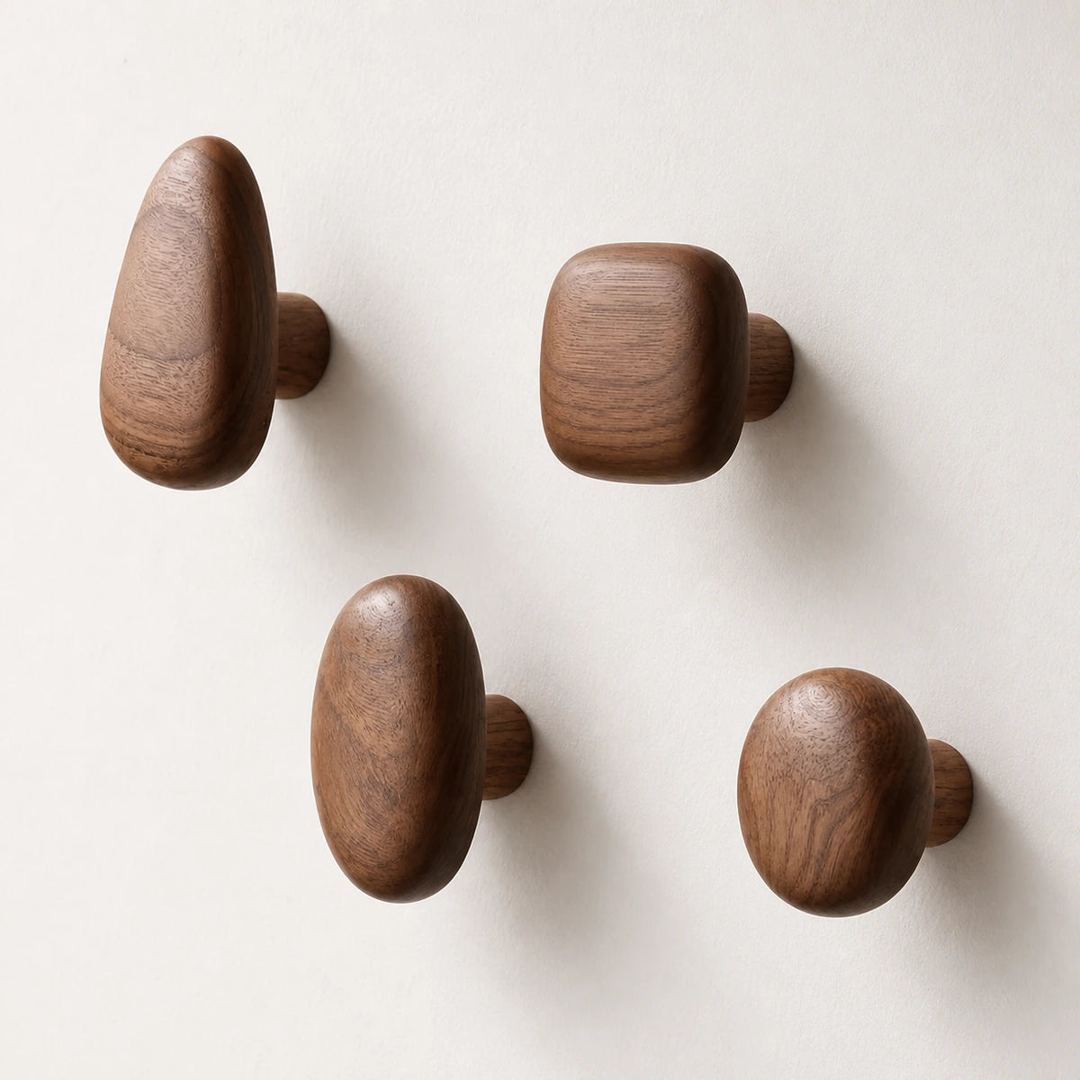 Set of four Walnut Wood organic pebble wall hooks on a clean light wall