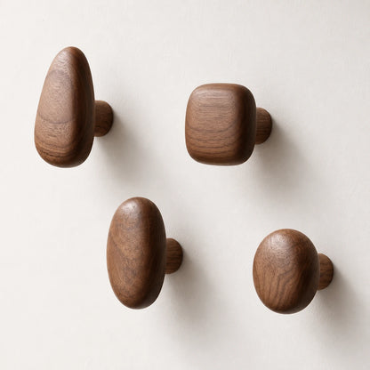 Set of four Walnut Wood organic pebble wall hooks on a clean light wall