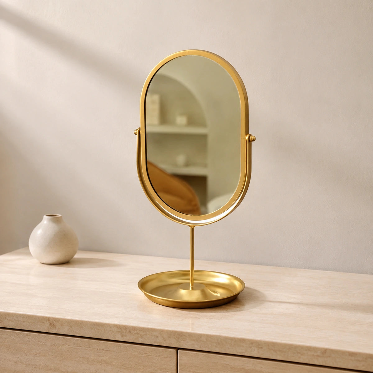 Gold oval vanity mirror on a refined dressing table