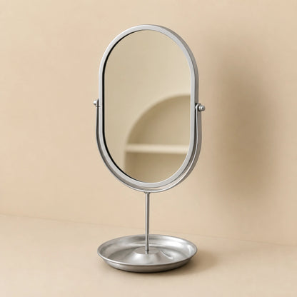Silver oval vanity mirror on a clean warm background