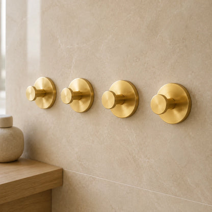 Gold vacuum suction wall hooks in a warm modern bathroom